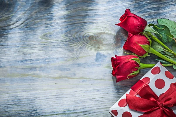 Krabičce s bow červené růže na dřevěné desce svátků konceptu — Stock fotografie