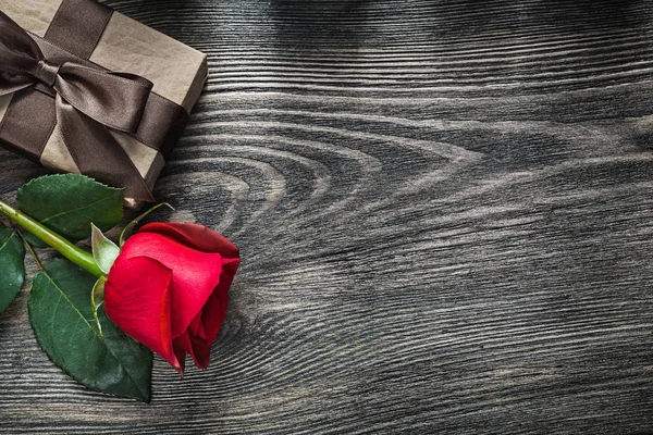 Red rose wrapped gift box on wooden board holidays concept — Stock Photo, Image