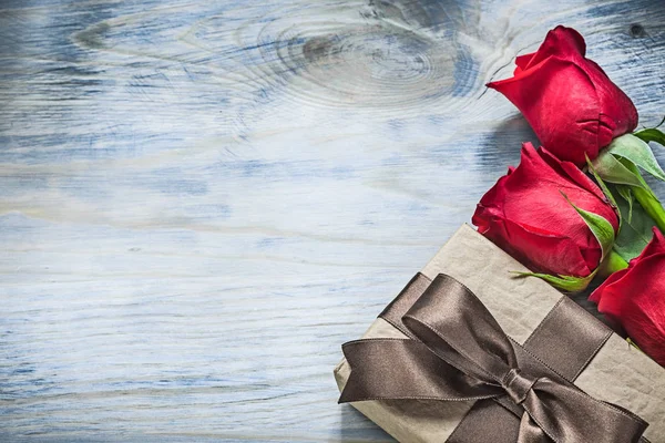 Conjunto de caja regalo envuelto rosas rojas en celebración de tablero de madera — Foto de Stock