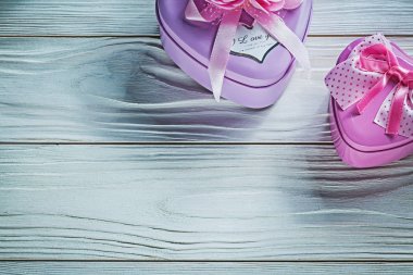 Metal kalp şeklindeki küçük mevcut kutuları ile ahşap üzerine pembe kurdeleler