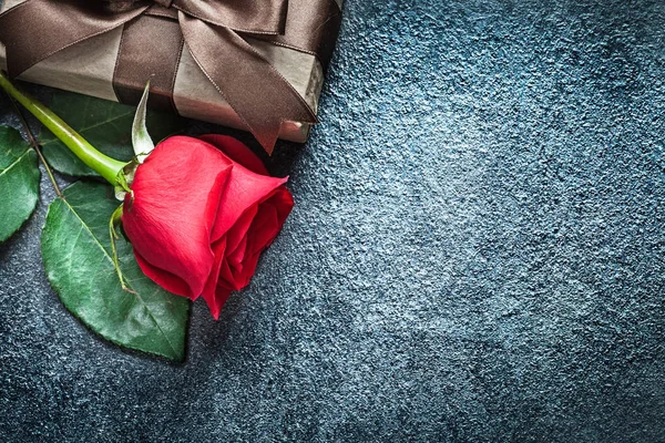 Dárková krabice s hnědou mašlí červená růže na černém pozadí svátků — Stock fotografie