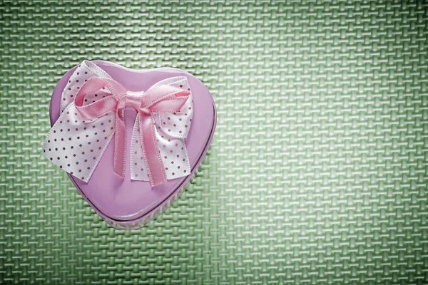Metalen roze hartvormige geschenkdoos met lint op groene achtergrond — Stockfoto