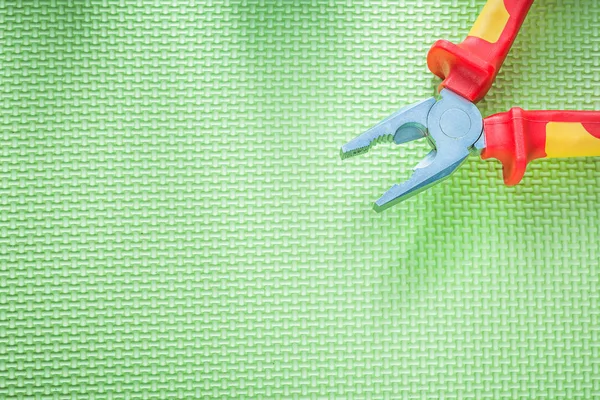 Insulation pliers on green background electricity concept