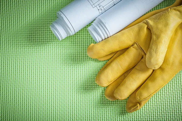 Safety leather gloves rolled blueprints on green background cons