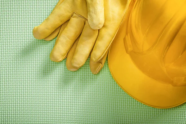 Geel gebouw helm beschermende handschoenen op groene achtergrond con — Stockfoto