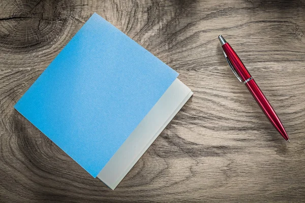 Vintage blue notepad red ballpoint pen on wooden board — Stock Photo, Image