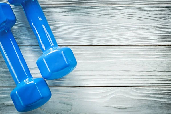 Blue dumbbells on wood board copy space sports training concept