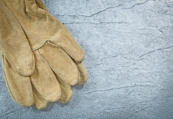 Pair of leather protective gloves on metallic background constru — Stock Photo, Image