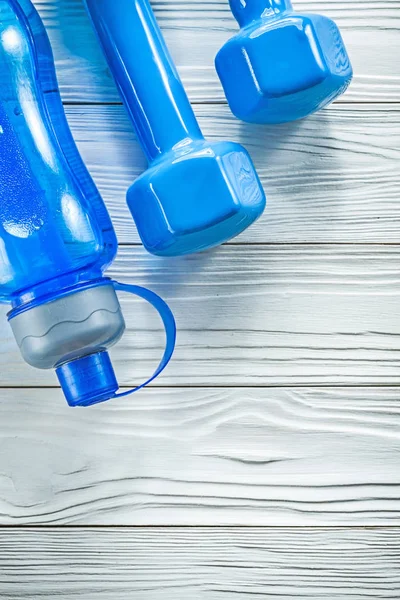 Botella de agua para atletismo mancuernas azules en deportes de mesa de madera — Foto de Stock