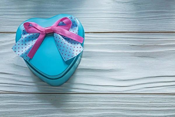 Herzförmige blaue Geschenkschachtel mit rosa Schleife auf Holzbrett Urlaub — Stockfoto
