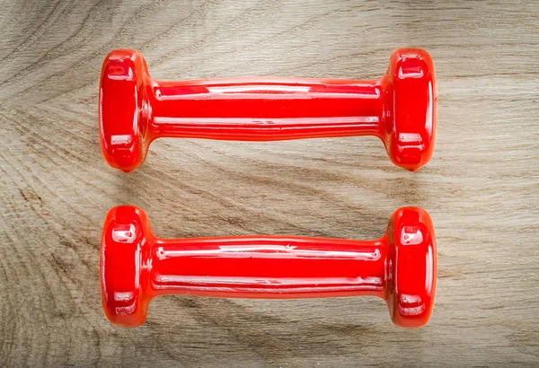 Par de pesos halteres vermelhos no conceito de aptidão da placa de madeira — Fotografia de Stock