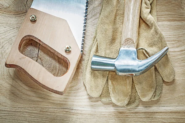 Klauenhammer Schutzhandschuhe scharfe Handsäge auf Holzbrett Nachteile — Stockfoto