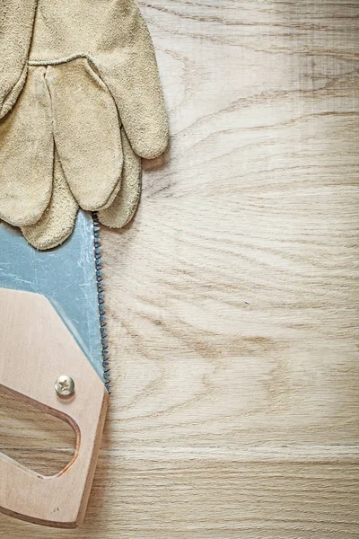 Kožené rukavice ostrou pilkou na dřevo konstrukce — Stock fotografie