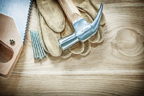 Set claw hammer veiligheid handschoenen handzaag nagels op houten plank c — Stockfoto