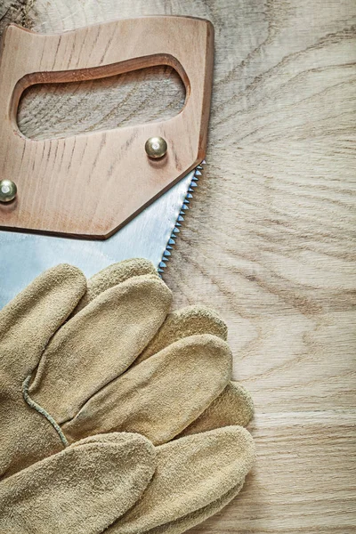 Afbeelding van de verticale van veiligheid handschoenen roestvrij Beugelzaag op houten zwijnen — Stockfoto