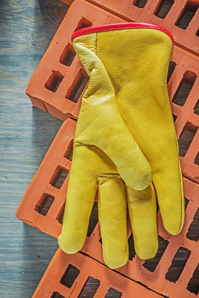 Guantes protectores de cuero ladrillos rojos sobre tabla de madera constructio — Foto de Stock