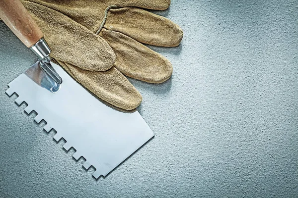 Paint scraper leather working gloves on concrete background cons