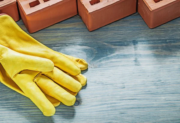 Ladrillos anaranjados guantes protectores amarillos en madera tablero bricklayi — Foto de Stock