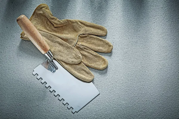 Bricklaying trowel leather protective gloves on concrete backgro