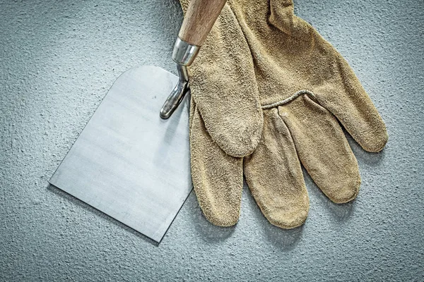 Stainless putty knife safety glove on concrete background constr