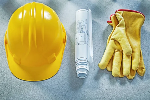 Building helmet protective gloves blueprints on concrete surface