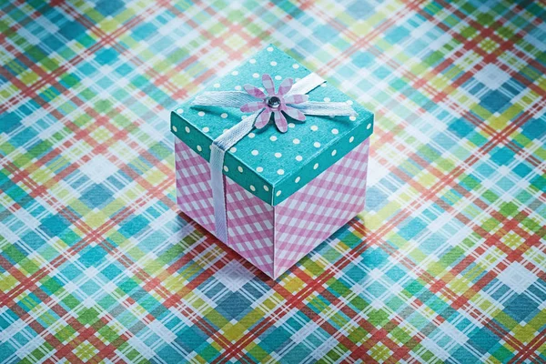 Boîte cadeau enveloppée sur fond de tissu à carreaux célébrations conce — Photo