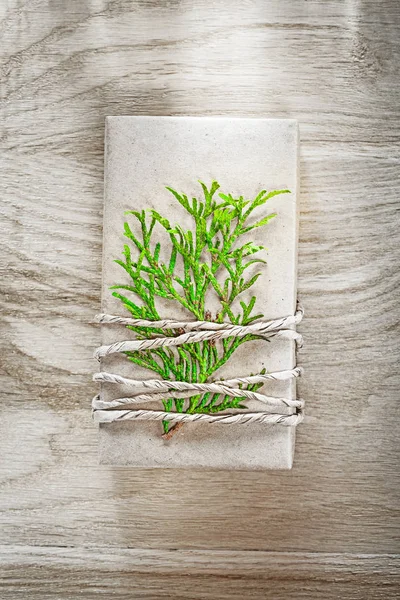 Handgefertigte Geschenkschachtel mit grünem Zweig auf Holzplatte — Stockfoto