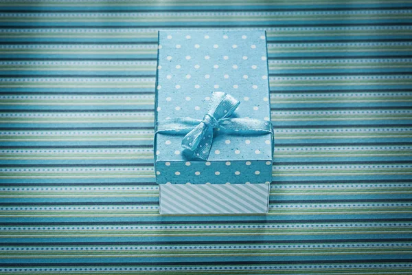 Синяя подарочная коробка на полосатый стол — стоковое фото