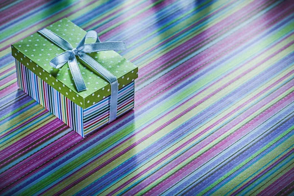 Cardboard present box with ribbon on striped tablecloth celebrat