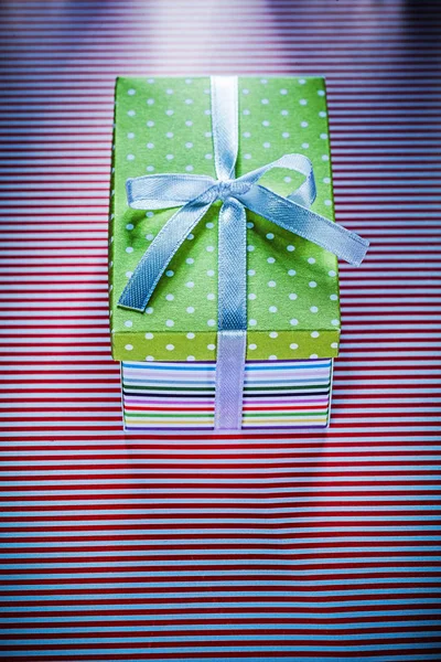 Cardboard box with present on red striped fabric celebrations co