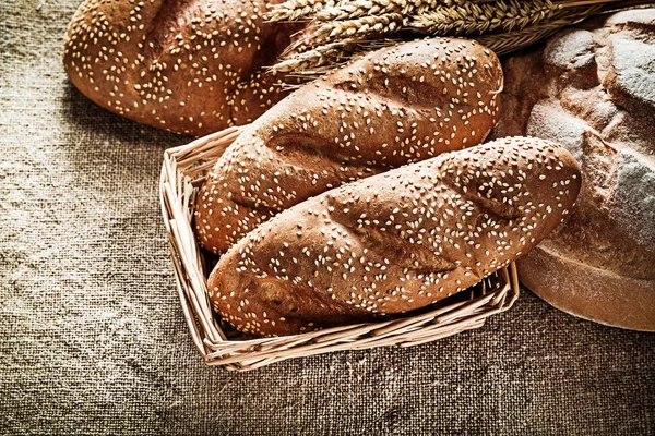Плетеная корзина хлебные палочки пшеничные уши на винтажном мешковине назад — стоковое фото