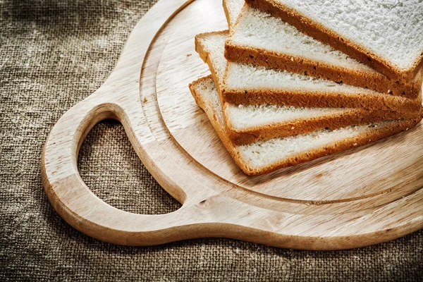 Chopping board sliced toast bread on textured sacking background — Stock Photo, Image