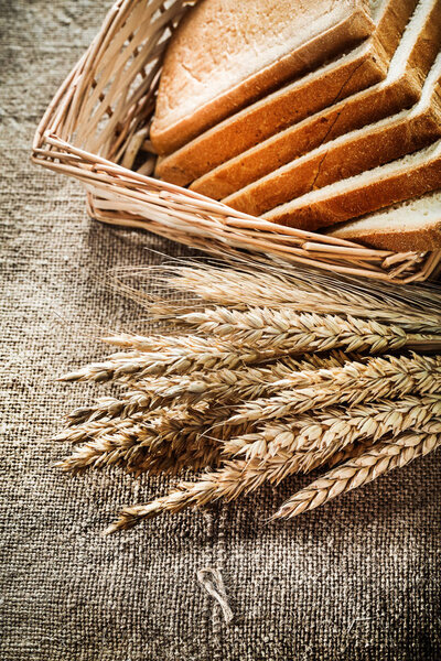 Wicker basket sliced bread rye ears on burlap background