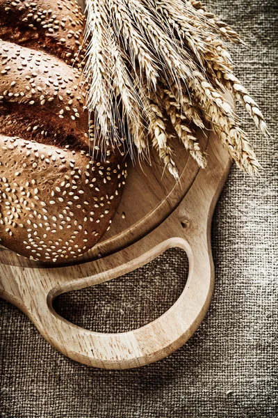 Doğrama kurulu ekmek çavdar kulakları üzerinde arka plan çuval bezi — Stok fotoğraf