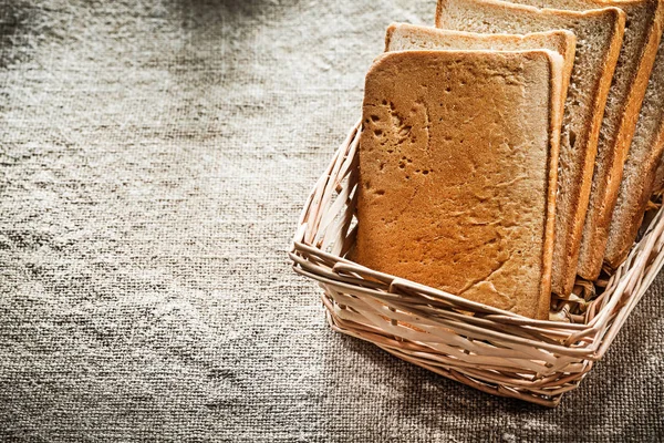 Плетеная корзина нарезанный хлеб на винтажном фоне мешок — стоковое фото