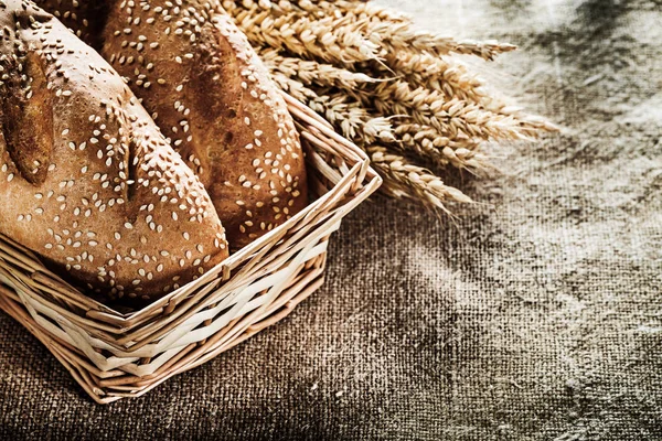 Wicker basket bread wheat ears on burlap background