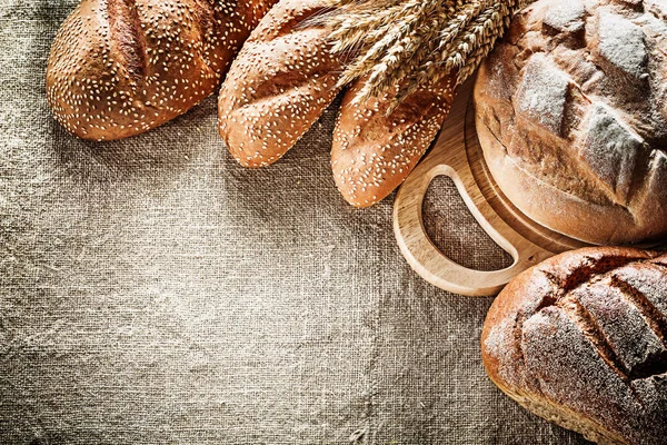 Schnitzbrett braunes Brot Baguette Weizenähren auf Säcken Backgro — Stockfoto