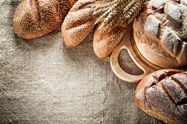 Carving board brown bread baguette wheat ears on sacking backgro