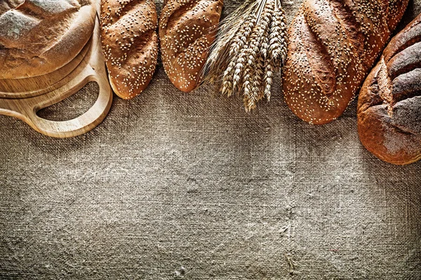 斩波板的棕色面包面包小麦耳朵上麻布背景 — 图库照片