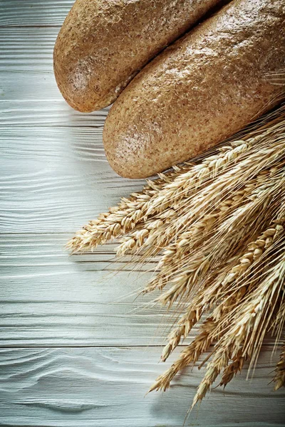 Baguete de trigo orelhas na tábua branca — Fotografia de Stock