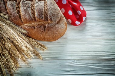 Kahverengi ekmek buğday kulakları kırmızı puantiyeli kumaş beyaz tahta üzerine