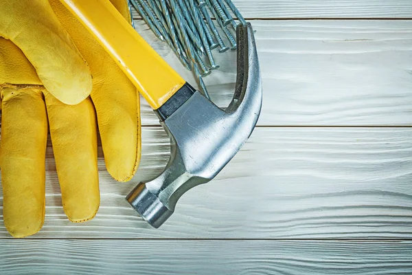 Beschermende handschoen claw hammer bouw nagels op houten bord — Stockfoto