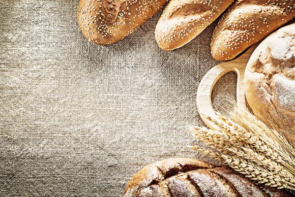 Kahverengi ekmek ekmeği doğrama kurulu backgr çuval bezi üzerinde çavdar kulaklar