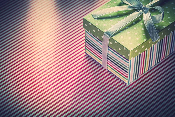 Present in cardboard box on red striped tablecloth celebrations