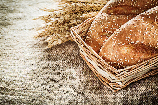 Wicker basket bread rye ears on burlap background