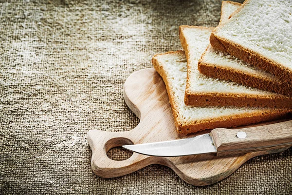 Chopping board kitchen knife sliced bread on hessian background