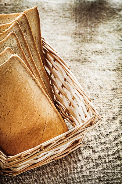 Weidenkorb in Scheiben geschnittenes Toastbrot auf Vintagepapier Hintergrund — Stockfoto