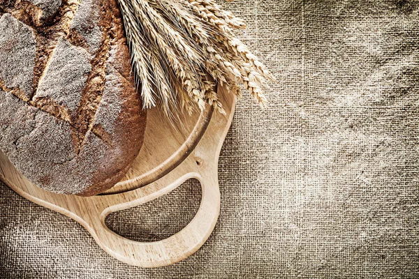Tabla de tallar pan manojo de espigas de trigo sobre fondo de arpillera —  Fotos de Stock