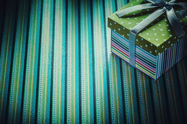 Present in cardboard box on striped background holidays concept — Stock Photo, Image