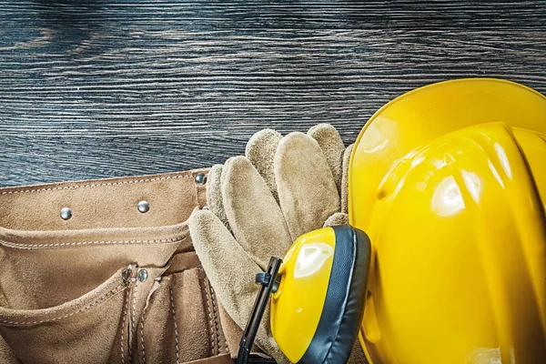 Gebouw helm oorkappen beschermende handschoenen toolbelt op hout zwijnen — Stockfoto